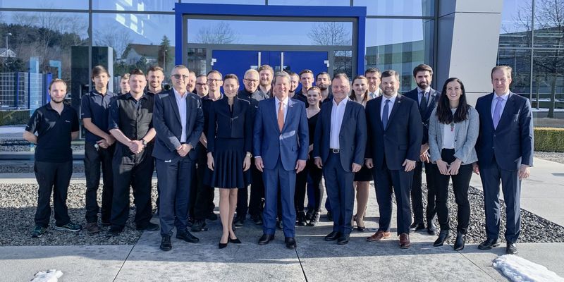 Geschäftsleitung von Häring steht mit dem Gouverneubesuch und den Mitarbeiter vor dem Gebäude von Häring und lächeln in die Kamera