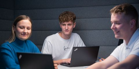 zwei Häring-Auszubildende sitzen in einer Besprechung vor Laptops und lachen