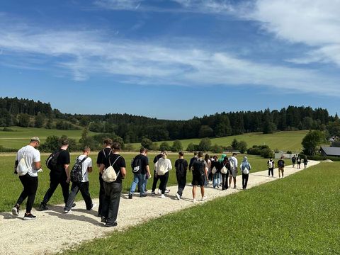 Häring-Azubis bei der Wanderung zwischen grünen Wiesen mit blauem Himmel